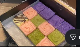 An open Ricci Chocolates gift box showing a grid of pastel-coloured ganache cubes in lilac, blush and pistachio